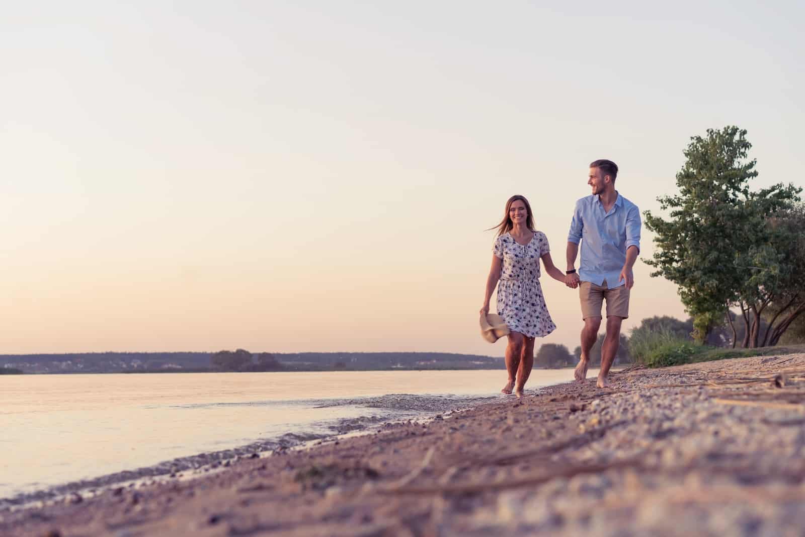One of the best lakes in Iowa for a couples trip this summer, happy couple walking along the shoreline in Okoboji
